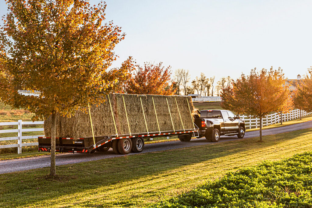 Beautiful evening sunset with truck and gooseneck trailer loaded with hay